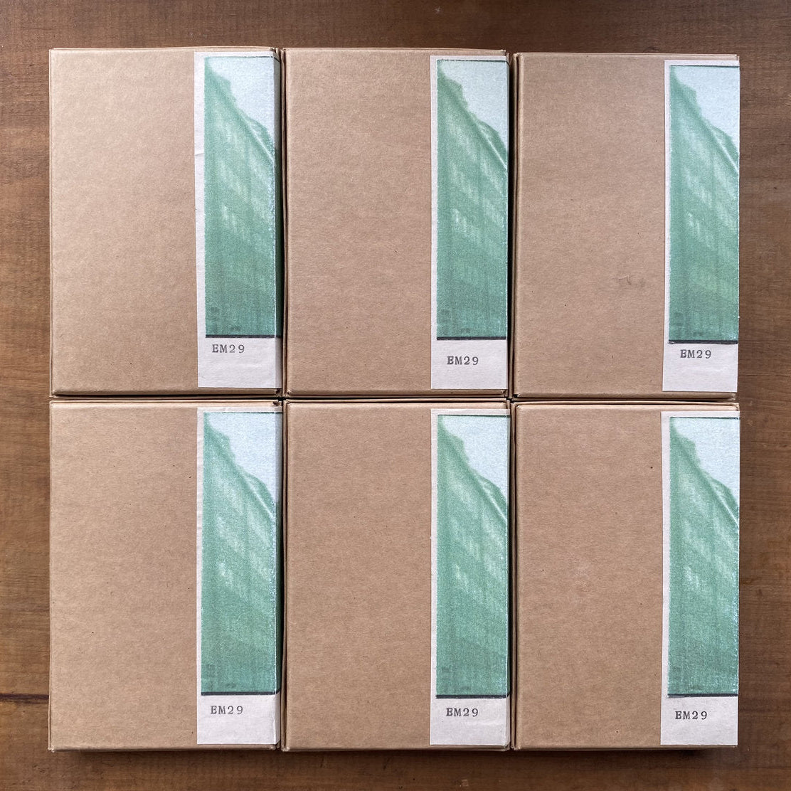 Six cardboard cassette boxes stacked on a wooden surface with green and white labels.