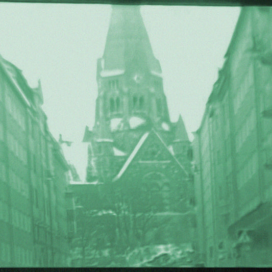 Narrow street with a prominent church building in the center, viewed through a textured green filter.