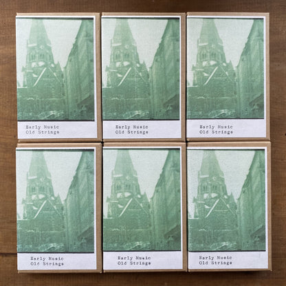 Six cassettes with a green and white design on a wooden surface