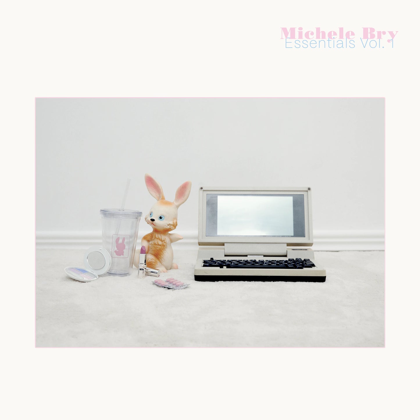 Small vintage-style laptop with a rabbit figurine and mug on a white surface, with 'Michele Bry Essentials Vol. 1' text.