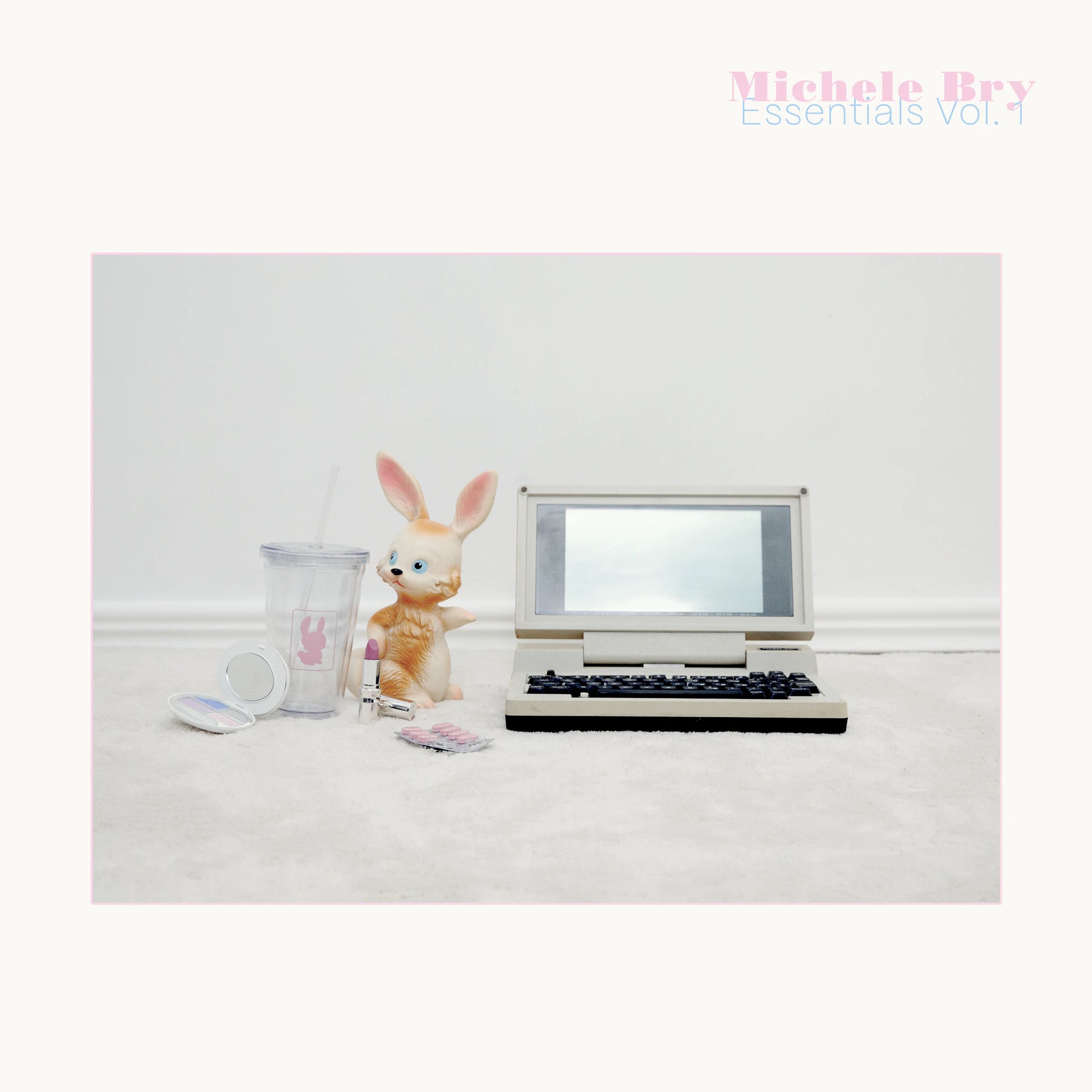Small vintage-style laptop with a rabbit figurine and mug on a white surface, with 'Michele Bry Essentials Vol. 1' text.
