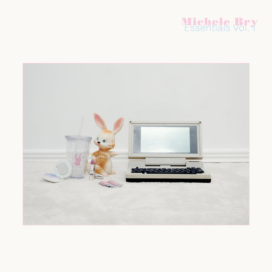 Small vintage-style laptop with a rabbit figurine and mug on a white surface, with 'Michele Bry Essentials Vol. 1' text.